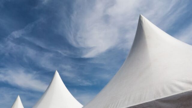 row of white event and party tents against blue sky